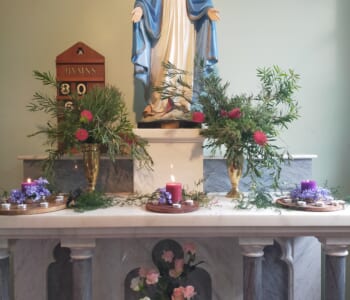 Altar in a Catholic church featuring a statue of Mary and floral arrangements