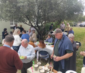 A large group of people gathered to celebrate and share a meal together outdoors