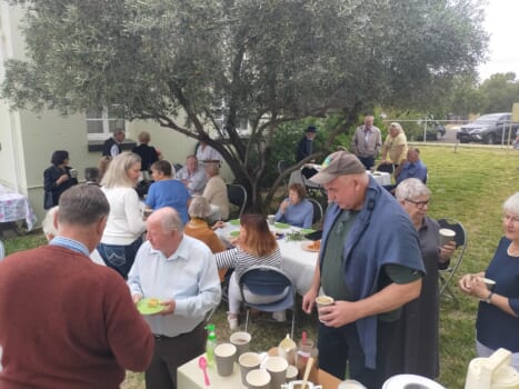A large group of people gathered to celebrate and share a meal together outdoors