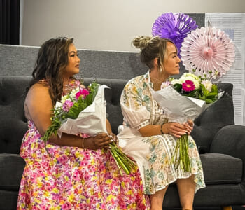 Two ladies seated holding bunches of flowers