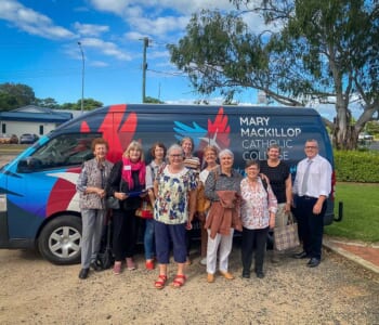 A group of people standing in front of a mini bus preparing for a trip