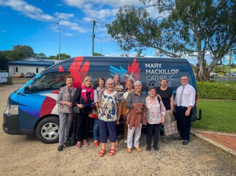 A group of people standing in front of a mini bus preparing for a trip