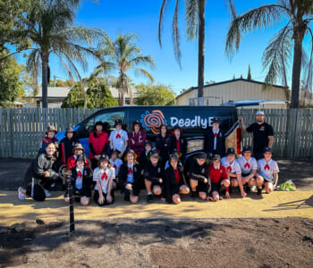 A group of smiling people posed in front of a van with the words "Deadly Ed" on it.