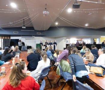 Four nuns in blue and white habits speaking to a large gathering of people