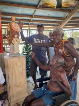 A group of First Nations Peoples from the Tiwi Islands pose with a statue of St Joseph