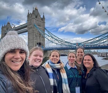 Group of smiling people posed in front of the London Bridge, London