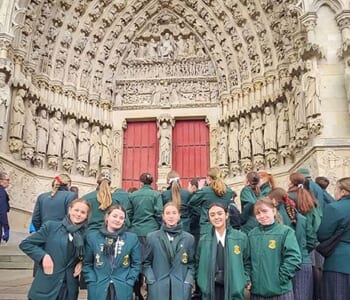 Group of school girls in green uniform pose in front of a door to Amiens Notore Dame Cathedral, Belgium