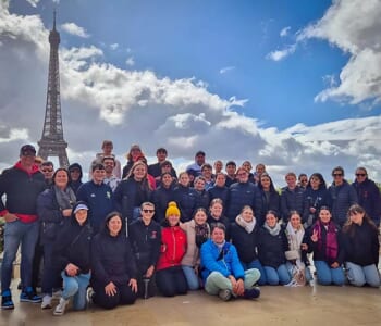 Group of smiling people posed in front of the Eiffel Tower, Paris