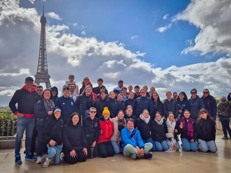 Group of smiling people posed in front of the Eiffel Tower, Paris