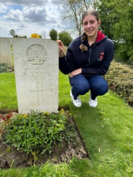 A girl poses next of a military headstone