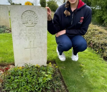 A girl poses next of a military headstone