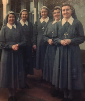 A vintage photo of a group of five nuns in grey and white habits